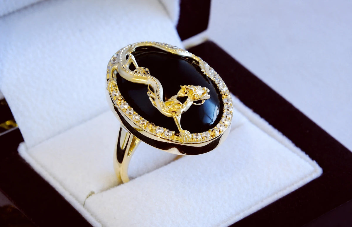 Oval ring i rosaguld med dragemotiv over sort gagat og diamanter omkring